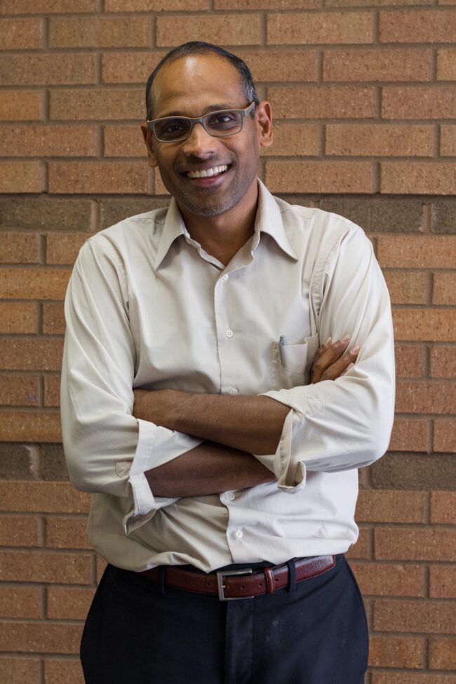Joseph Pathakamuri Faculty Photo Portrait of Dr. Joseph Pathakamuri standing in front of a brick wall.