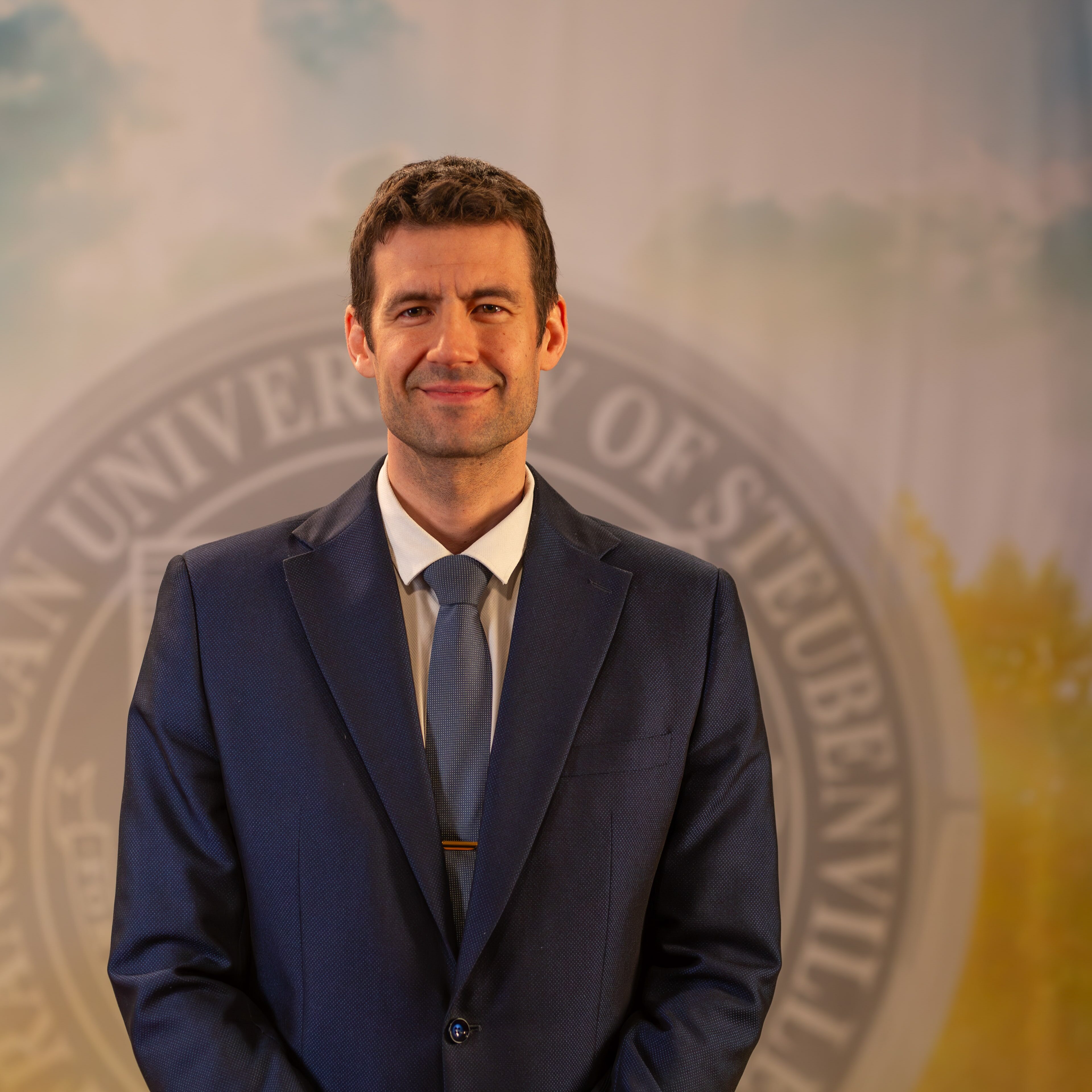 To Web – Bartosz Langowski FEB2025 –8 Dr. Bartosz Langowski standing in front of a university seal.