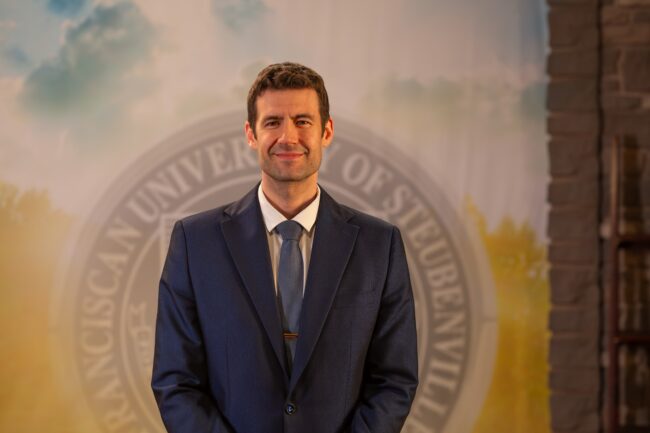 To Web – Bartosz Langowski FEB2025 –8 Dr. Bartosz Langowski standing in front of a university seal.