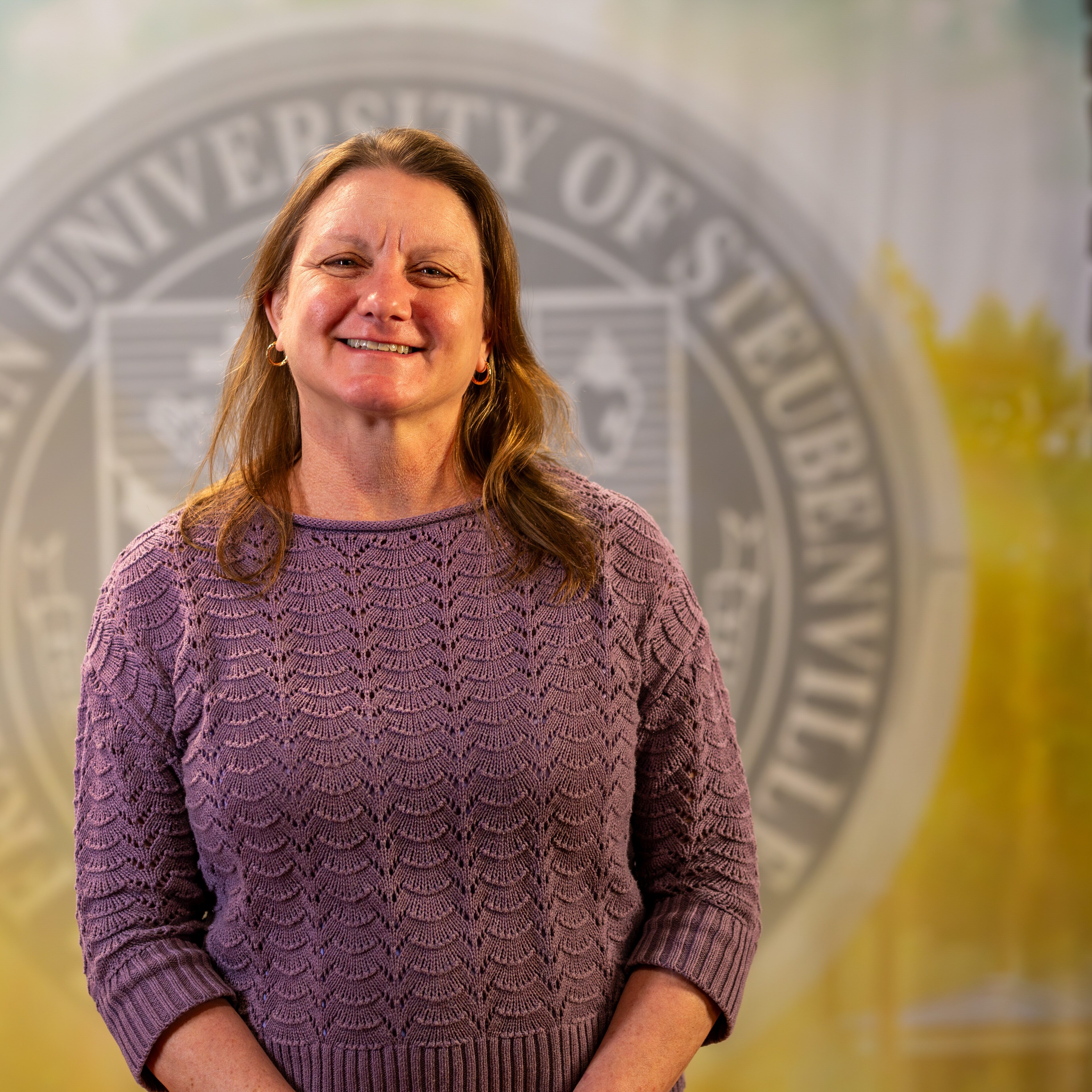 To Web – Denise Lombard FEB2025 –5 Denise Lombard standing in front of a university seal.