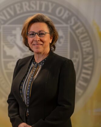 Julie Smith standing in front of a university seal