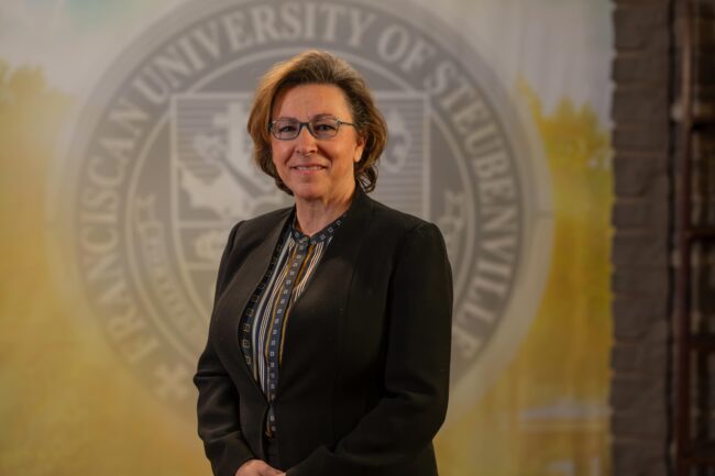Julie Smith standing in front of a university seal