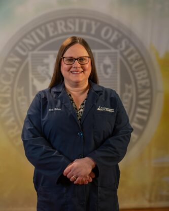 Tanya Dillion standing in front of a university seal.